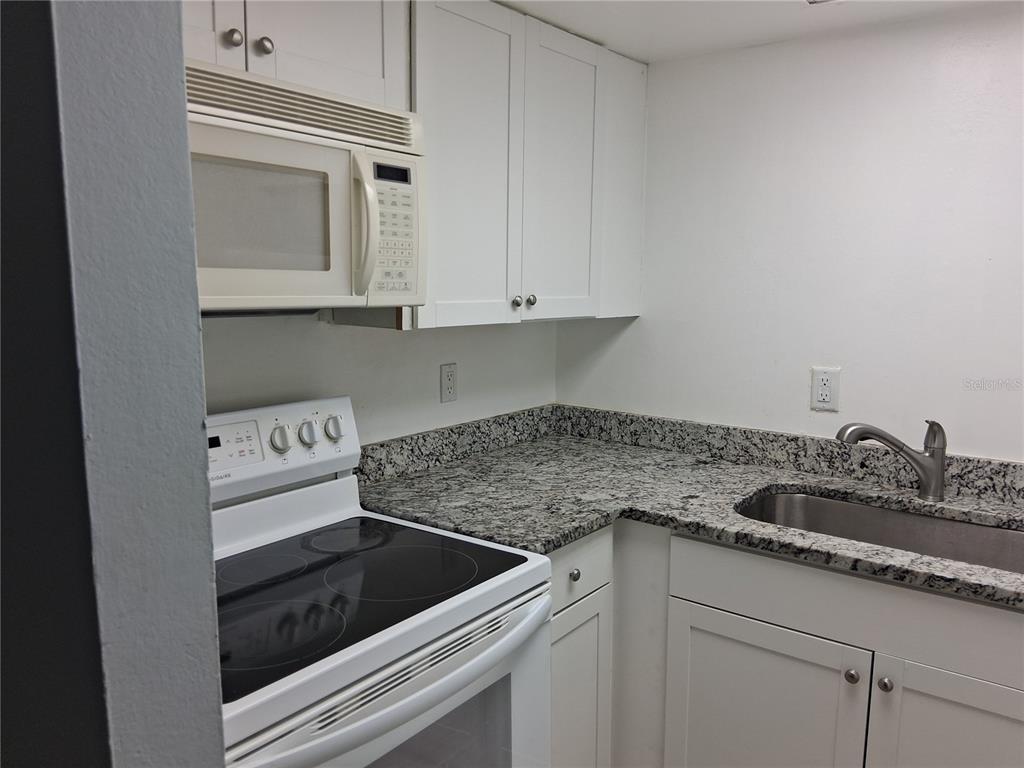 958 Lake Destiny Road, Unit D Altamonte Springs, FL 32714 - Photo 6 of 16 a kitchen with granite countertop white cabinets and white appliances