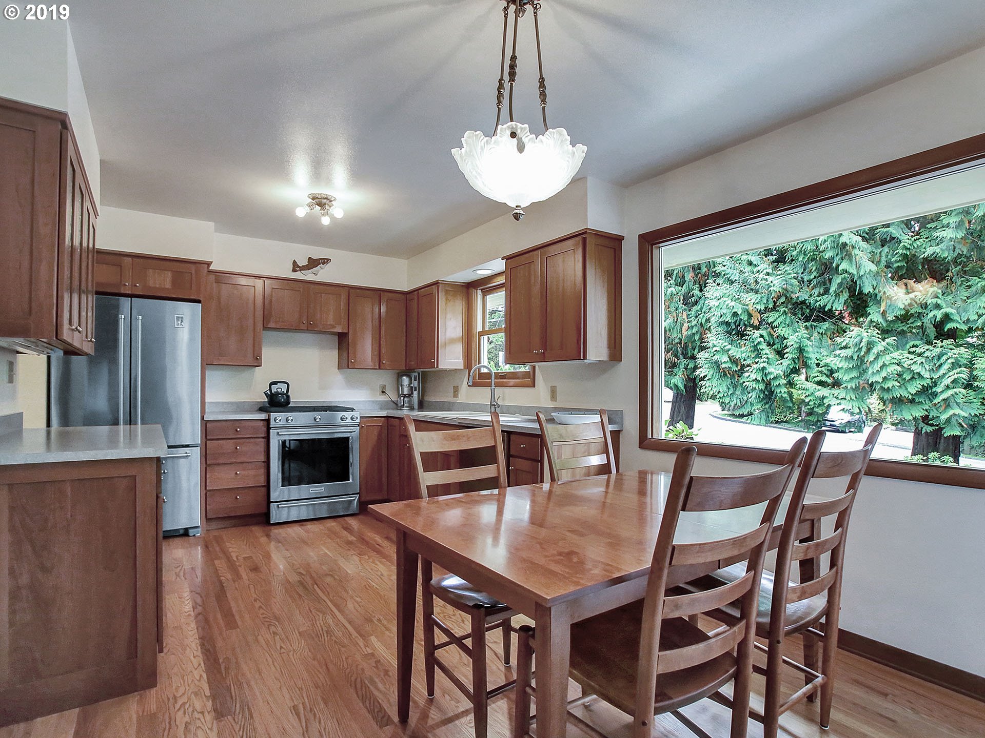 4119 Southwest Hamilton Street Portland, OR 97221 - Photo 6 of 29 a kitchen with stainless steel appliances granite countertop a stove a refrigerator a sink dishwasher a dining table and chairs with wooden floor