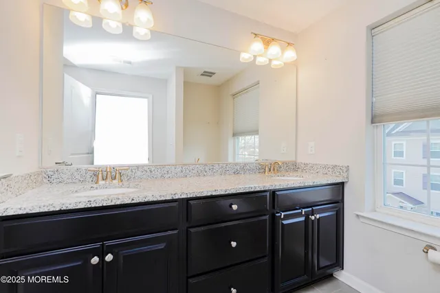 a bathroom with a granite countertop sink a large mirror and a wooden cabinets
