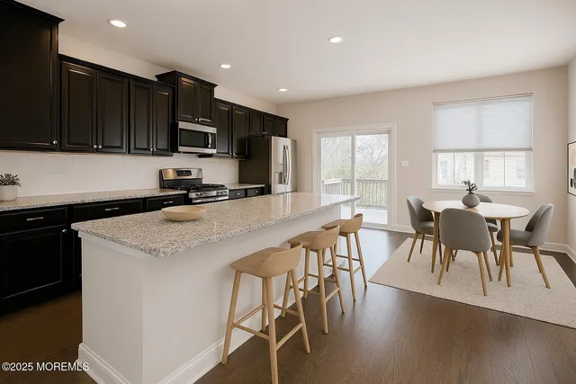 a kitchen with stainless steel appliances kitchen island granite countertop a table chairs microwave and sink