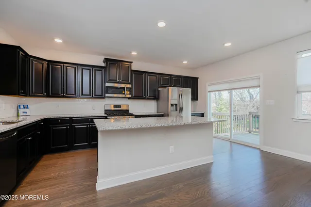 a kitchen with stainless steel appliances granite countertop a refrigerator a stove top oven a sink and dishwasher with wooden floor