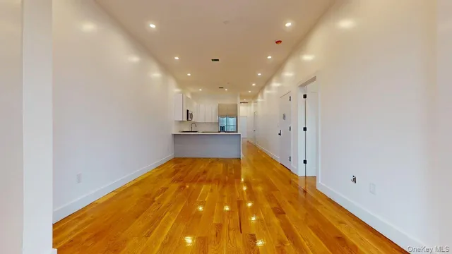 a view of kitchen and empty room with wooden floor