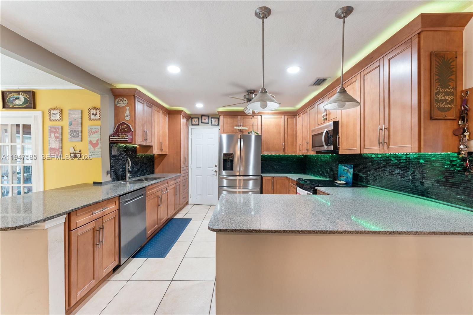 10100 Southwest 50th Court Cooper City, FL 33328 - Photo 6 of 24 a large kitchen with kitchen island a large counter top stainless steel appliances and cabinets