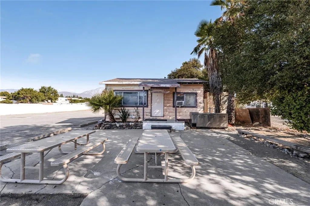 10026 Foothill Boulevard Rancho Cucamonga, CA 91730 - Photo 16 of 34 a view of a patio with table and chairs under an umbrella with large trees