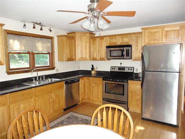 253 NW Road Westhampton, MA 01027 - Photo 4 of 16 a kitchen with stainless steel appliances granite countertop a refrigerator a sink dishwasher a stove and a dining table with wooden floor