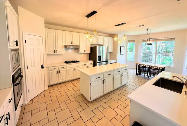 a large white kitchen with cabinets appliances and a large window