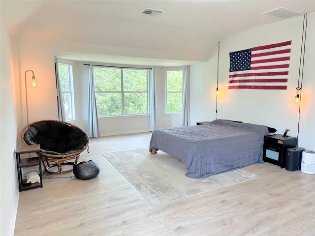 a spacious bedroom with a bed and wooden floor