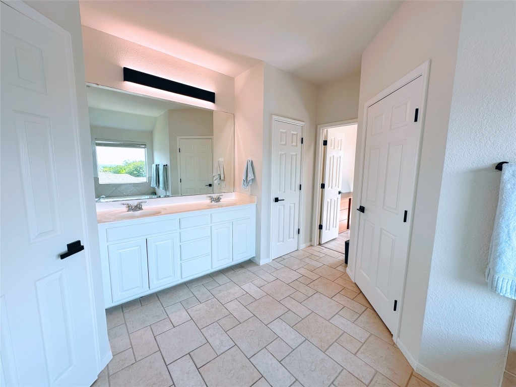 12504 Gun Metal Drive Austin, TX 78739 - Photo 22 of 40 a spacious bathroom with a mirror a double vanity sink and mirror