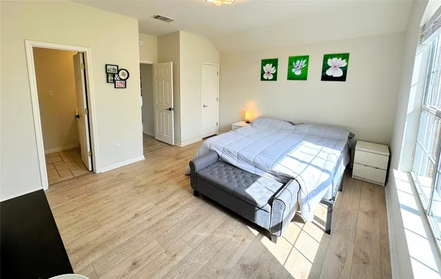 a bedroom with a bed a tv and wooden floor