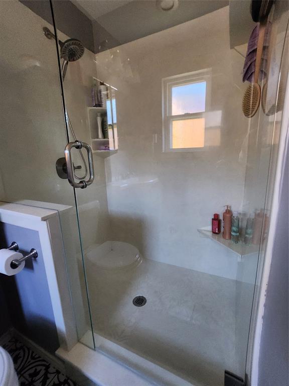 1023 Ridgefield Drive Plano, TX 75075 - Photo 31 of 40 Glass-enclosed shower with a multi-function showerhead, built-in shelving, and a small window for natural illumination