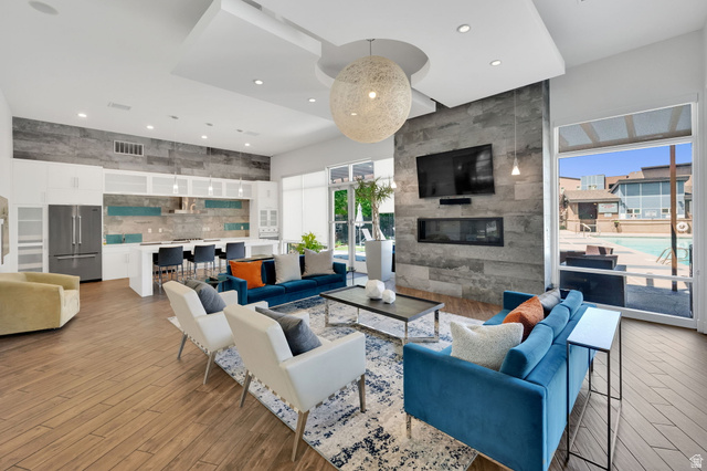 7713 Navarro View Court Midvale, UT 84047 - Photo 34 of 41 Open-concept living space with wood-finish flooring, a contemporary fireplace feature wall, a full kitchen with stainless steel appliances, and large windows overlooking a swimming pool
