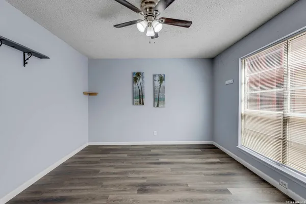a view of empty room with wooden floor and fan