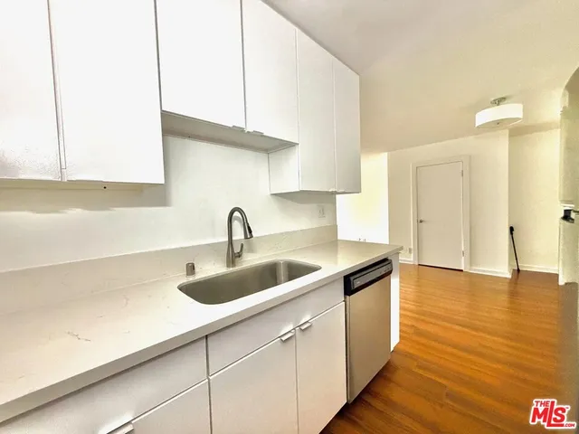 an empty room with wooden floor cabinet and windows