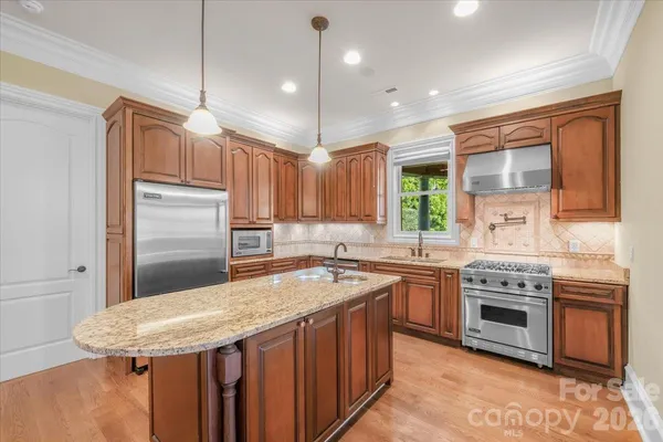 a kitchen with stainless steel appliances granite countertop refrigerator a stove a sink and a microwave