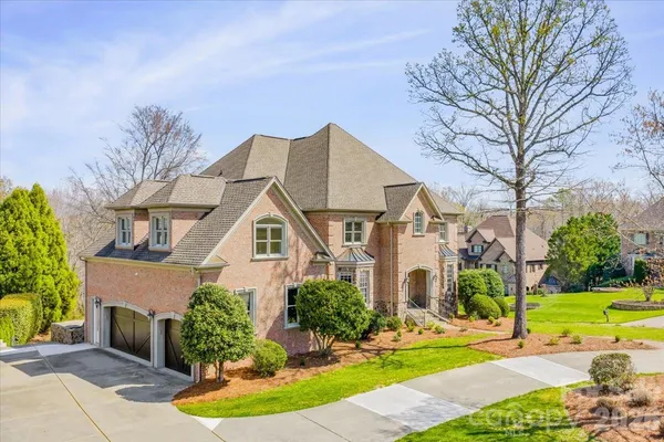 a front view of a house with garden and trees
