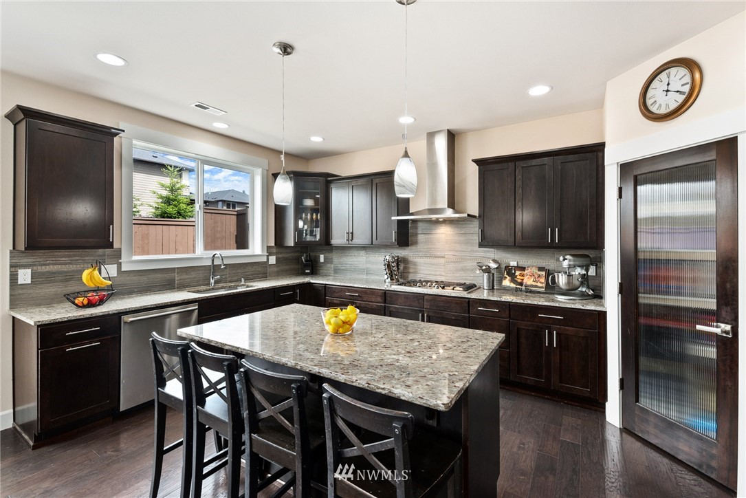 4113 172nd Place Southeast Bothell, WA 98012 - Photo 11 of 32 a kitchen with stainless steel appliances granite countertop a sink a stove a dining table and chairs