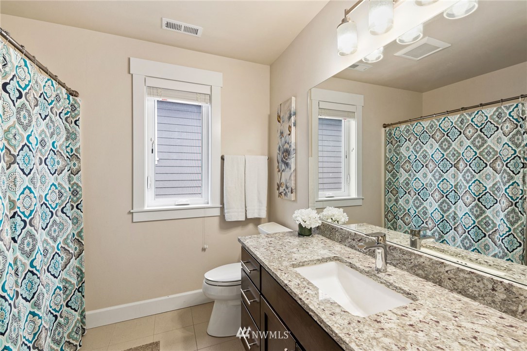 4113 172nd Place Southeast Bothell, WA 98012 - Photo 25 of 32 a bathroom with a granite countertop toilet a sink a mirror a vanity and a shower