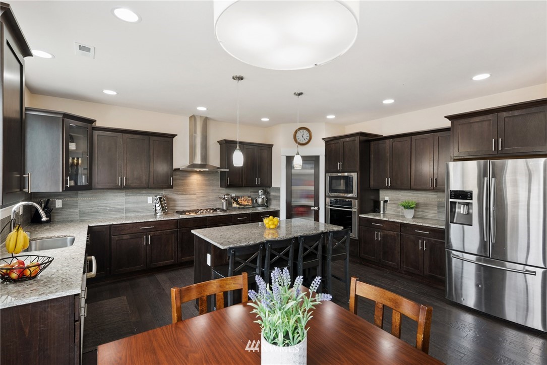 4113 172nd Place Southeast Bothell, WA 98012 - Photo 31 of 32 a kitchen with stainless steel appliances granite countertop a refrigerator a stove a sink a microwave dining table and chairs