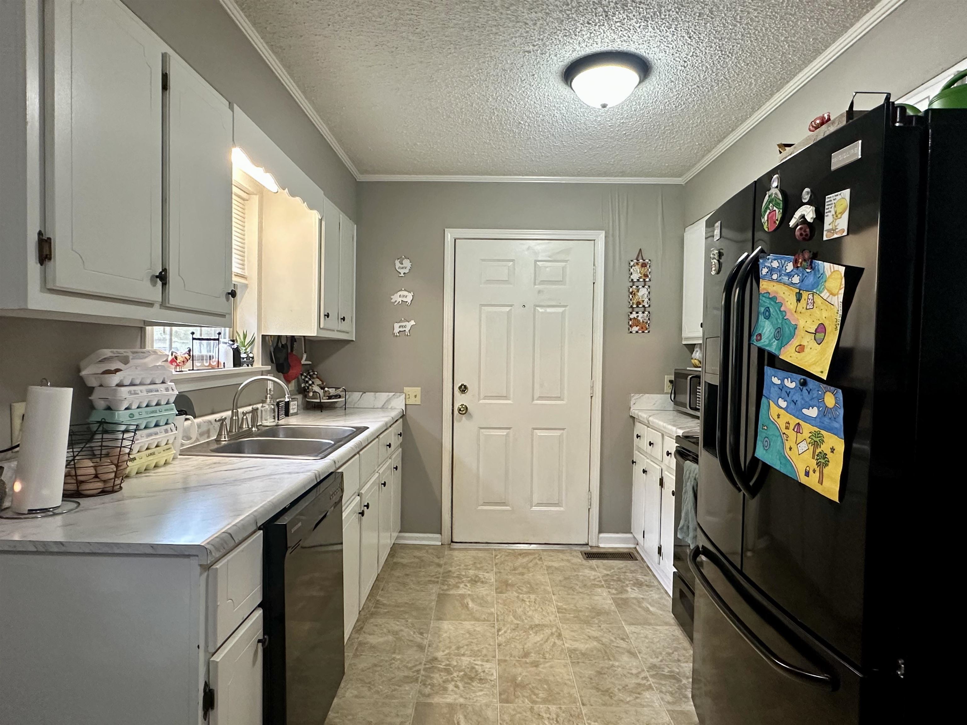 320 Clayton Road Finger, TN 38334 - Photo 4 of 16 Kitchen with black appliances, white cabinets, light countertops, ornamental molding, and a textured ceiling