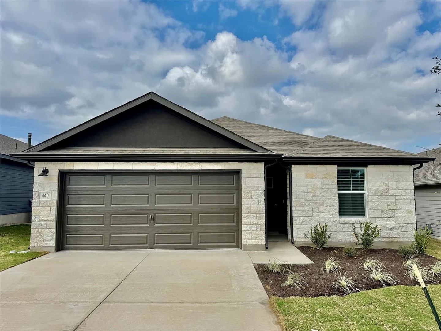 Ranch-style house featuring stone siding, concrete driveway, a garage, and a shingled roof