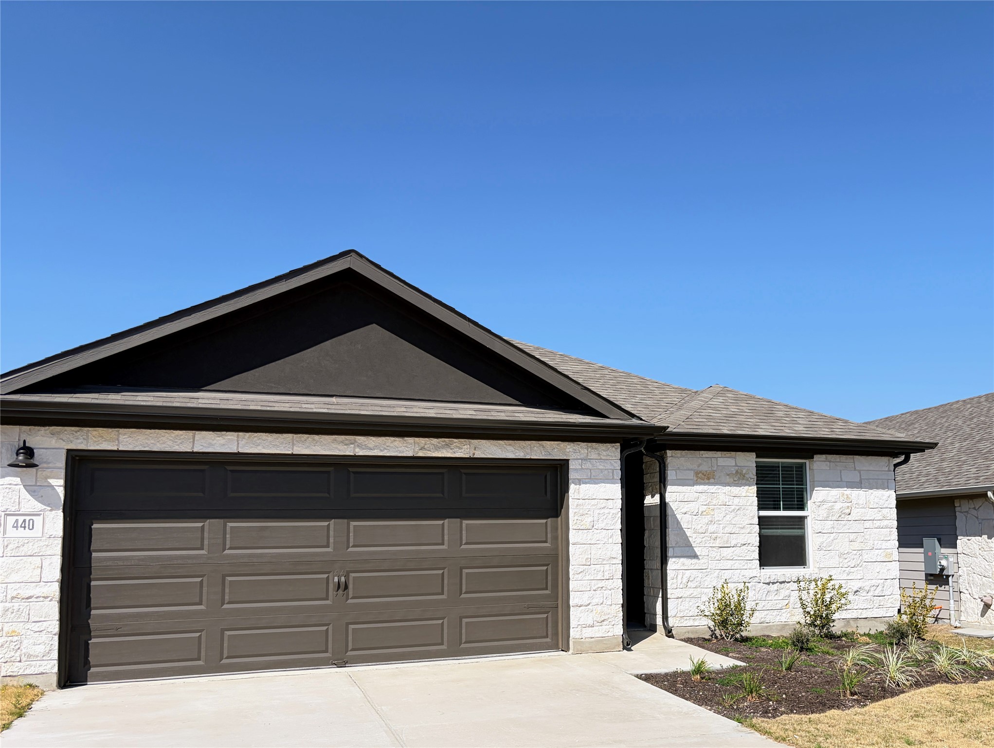 440 El Capitan Loop Dripping Springs, TX 78620 - Photo 3 of 22 Ranch-style house featuring stone siding, concrete driveway, an attached garage, and a shingled roof