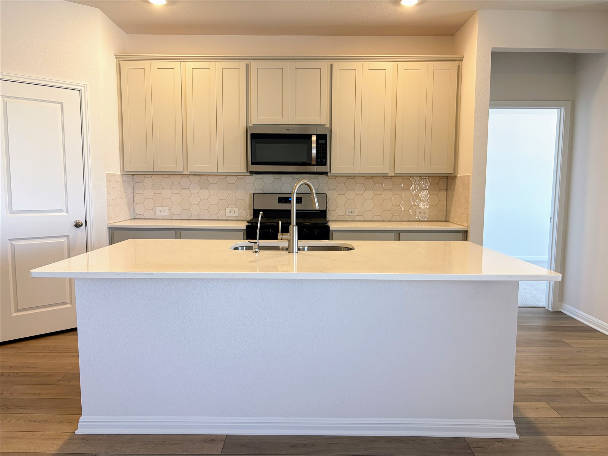 440 El Capitan Loop Dripping Springs, TX 78620 - Photo 5 of 22 Kitchen with backsplash, stainless steel appliances, light wood LVP flooring, and light stone counters