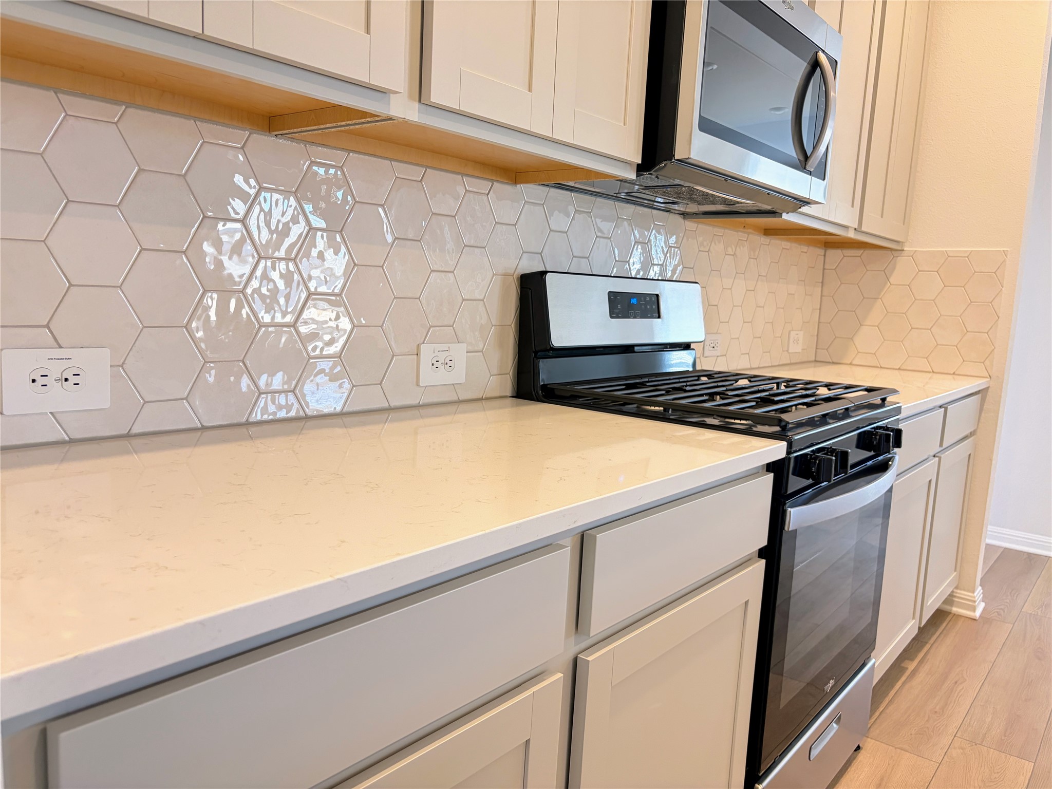 440 El Capitan Loop Dripping Springs, TX 78620 - Photo 6 of 22 Kitchen with stainless steel appliances, light wood finished floors, light stone counters, and decorative backsplash