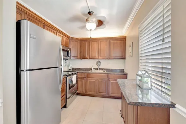 a kitchen with stainless steel appliances granite countertop a refrigerator a sink dishwasher a stove a dining table and chairs with wooden floor