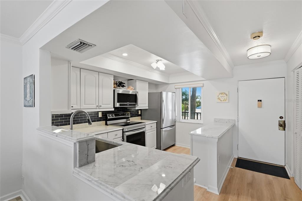 8977 Midnight Pass Road, Unit 223 Sarasota, FL 34242 - Photo 4 of 82 a kitchen with stainless steel appliances granite countertop a refrigerator stove microwave and sink