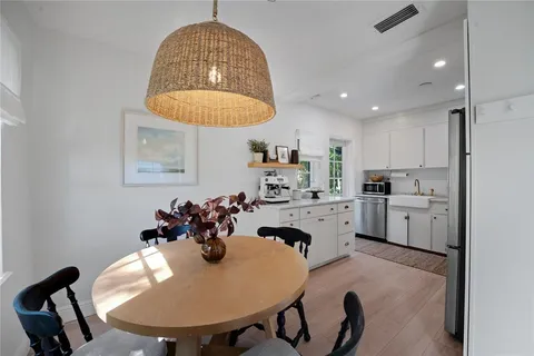a kitchen with stainless steel appliances granite countertop a sink a stove a dining table and chairs