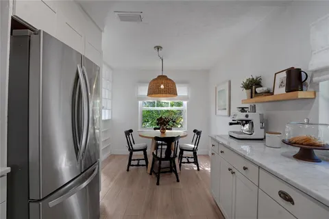 a kitchen with stainless steel appliances granite countertop dining table chairs and wooden floor