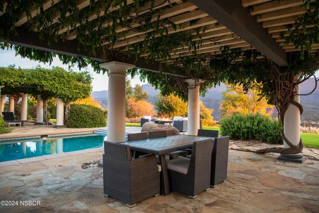 a view of a white house with a big yard and potted plants