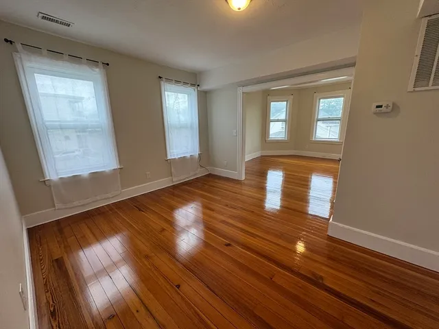 a view of an empty room with wooden floor and a window