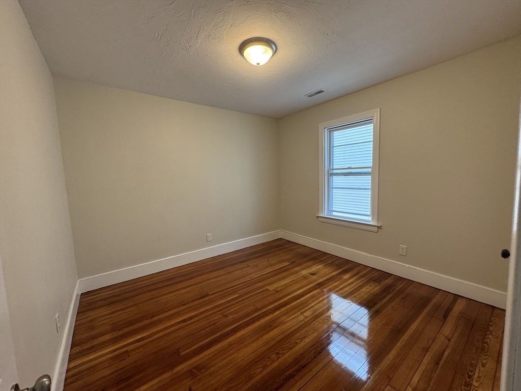 72 Forest Street, Unit 2 Attleboro, MA 02703 - Photo 7 of 10 a view of an empty room with wooden floor and a window