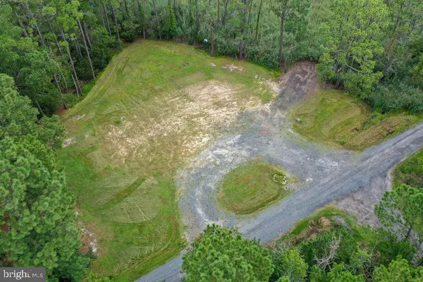 an aerial view of a residential houses with outdoor space and trees all around