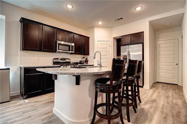 a kitchen with stainless steel appliances kitchen island granite countertop a refrigerator and a stove top oven