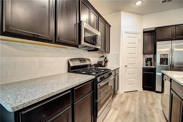 a kitchen with stainless steel appliances granite countertop a stove refrigerator and microwave