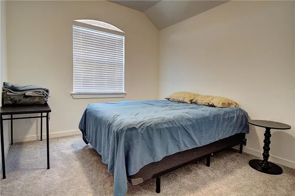 a bedroom with a bed and two window