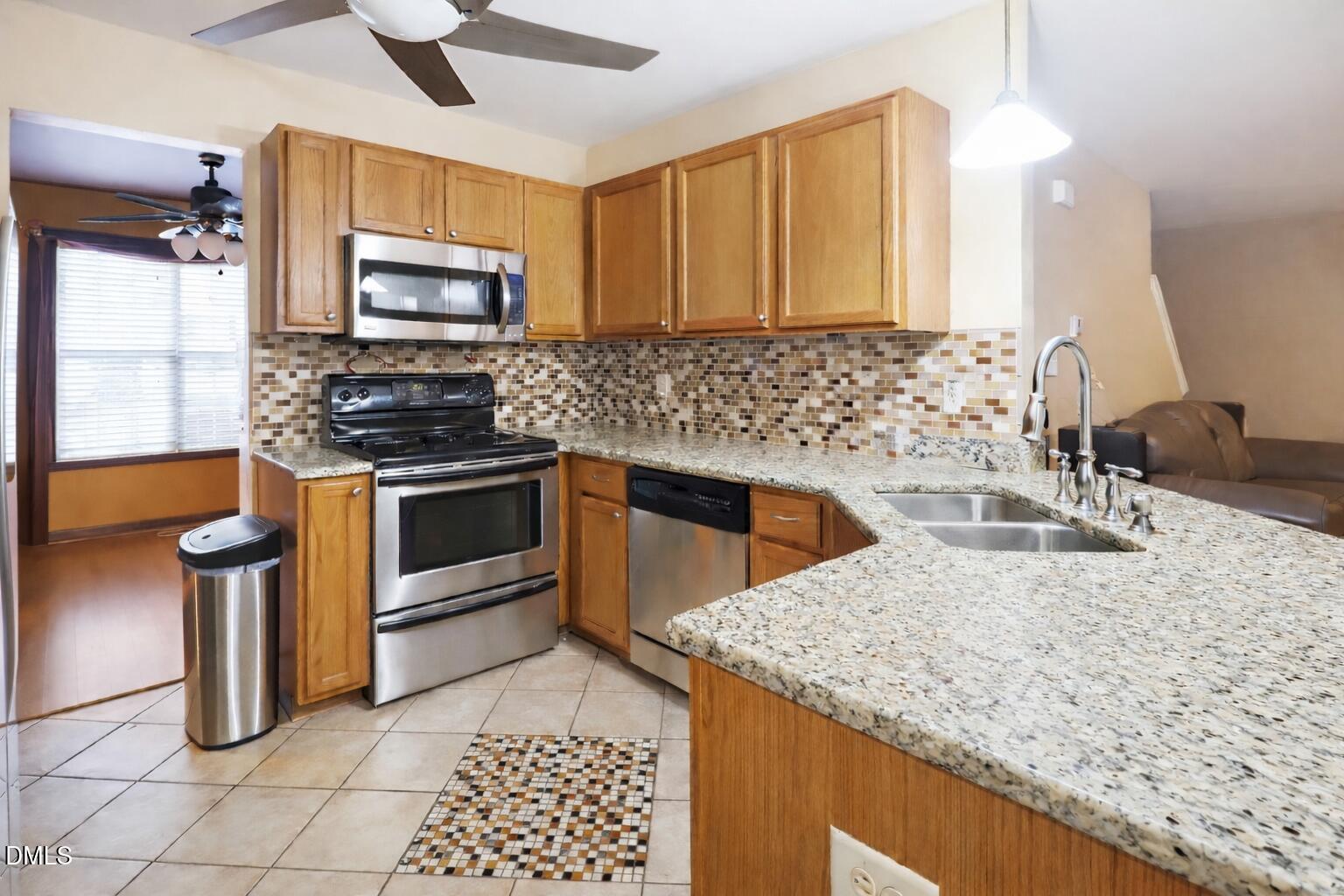 1504 Springshire Court Raleigh, NC 27610 - Photo 4 of 16 a kitchen with granite countertop a sink a stove and a microwave