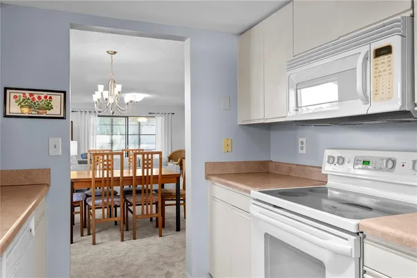 a kitchen that has a cabinets counter space dining table and a chandelier