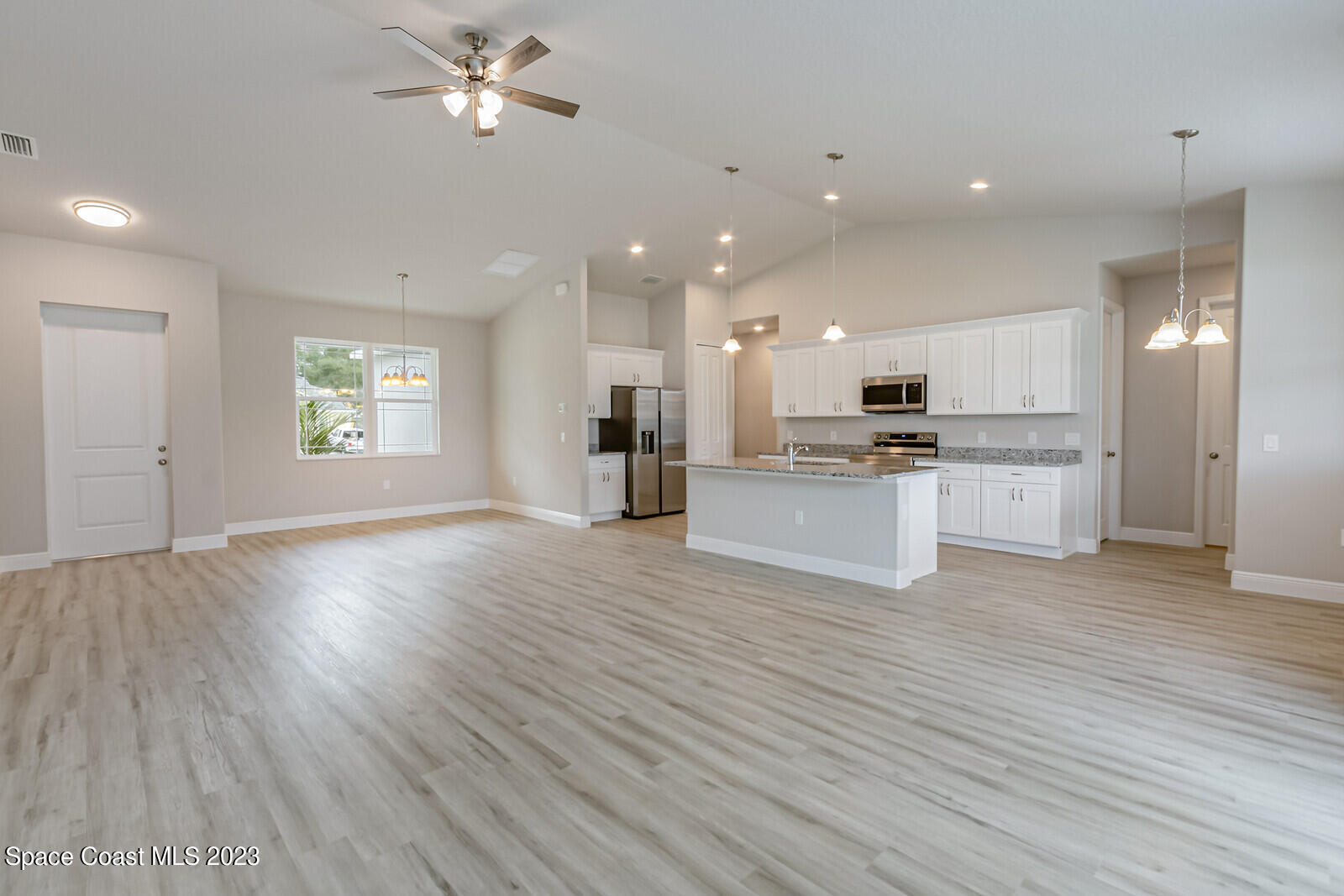 931 Thompson Road Southwest Palm Bay, FL 32908 - Photo 24 of 24 a view of an empty room with wooden floor and a kitchen