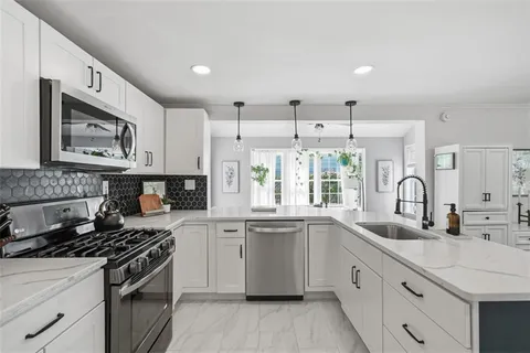 a kitchen with granite countertop a sink cabinets stainless steel appliances and a window