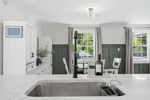 a kitchen with a sink and a potted plant with wooden floor