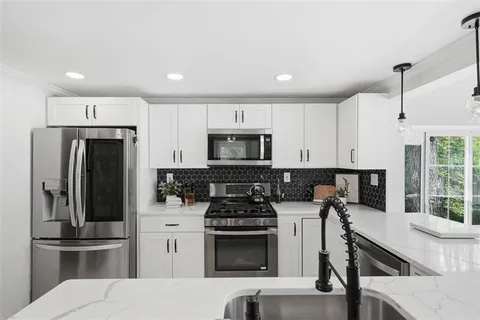 a kitchen with stainless steel appliances a stove a sink a refrigerator and cabinets