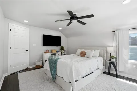 a bedroom with a bed and a flat tv screen on wall