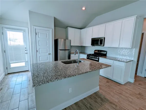 a kitchen with stainless steel appliances granite countertop a sink a stove a refrigerator a microwave and cabinets