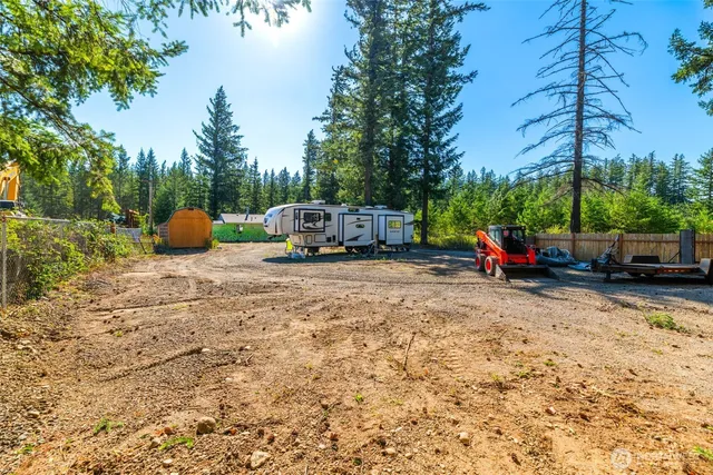 a view of a backyard with large trees and wooden fence