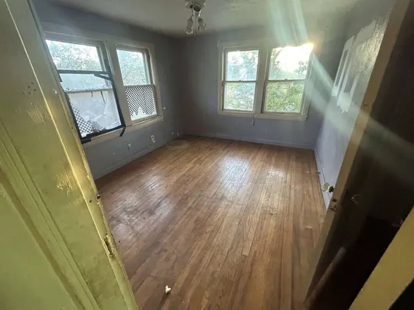 a view of an empty room with wooden floor and windows