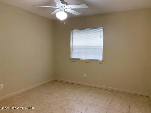an empty room with a chandelier fan and windows