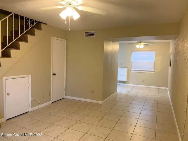 a view of an empty room with wooden floor and a chandelier